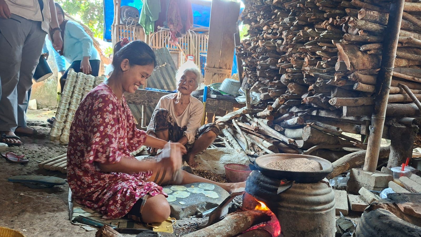 Warga memipihkan emping melinjo di atas batu di dekat tungku kayu di Desa Tembong.
